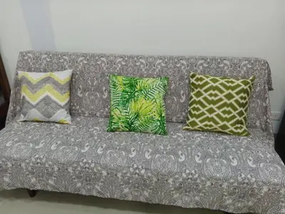 a gray couch with four pillows on it at S Suite Home MOA Staycation in Manila