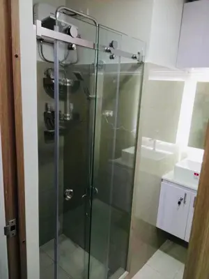 a glass shower in a bathroom with a sink at S Suite Home MOA Staycation in Manila
