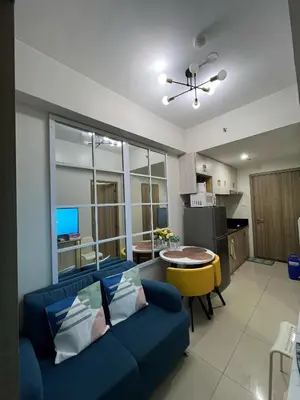 a living room with a blue couch and a kitchen at Key and Stay in Manila