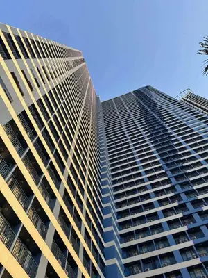 a large tall building with a palm tree in front of it at Affordable Staycation Home in Makati in Manila