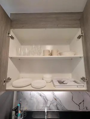 a kitchen cabinet with plates and glasses on it at Cozy Modern Sunset View in Manila