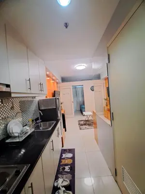 a kitchen with white cabinets and a black counter top at Sarah's Staycation at Sea Residences Near Moa in Manila