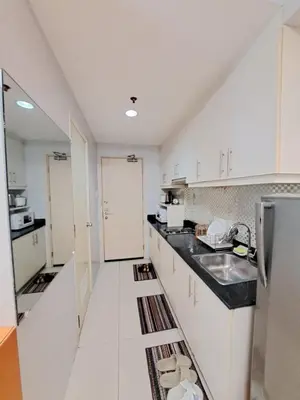 a white kitchen with a sink and a refrigerator at Sarah's Staycation at Sea Residences Near Moa in Manila