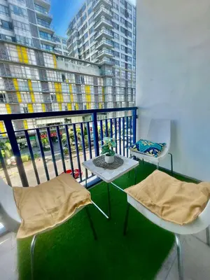 a balcony with two chairs and a table and a large window at Sarah's Staycation at Sea Residences Near Moa in Manila