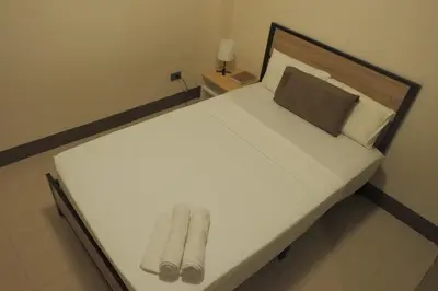 a white bed with two pairs of slippers on it at Brightwood Hotel & Residences in Manila