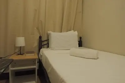 a white bed with a pillow and a lamp on a table at Brightwood Hotel & Residences in Manila