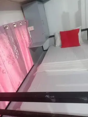 a small room with a bed with a red pillow at Sean Lojed Hostel in Manila