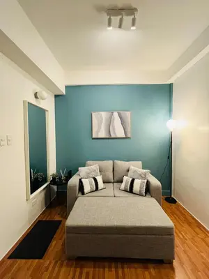 a living room with a couch and a blue wall at Cedrosa Lofts GA Tower in Manila