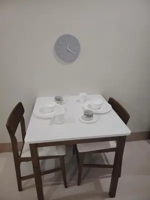 a table with two chairs and a clock on the wall at Shore 3 Tower 30372 in Manila
