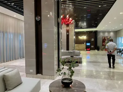 a man is standing in a lobby with a table at Cozy Condo Apartment in Red Residences Makati near malls and airport in Manila