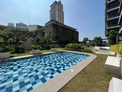 a swimming pool with a tall building in the background at Cozy Condo Apartment in Red Residences Makati near malls and airport in Manila