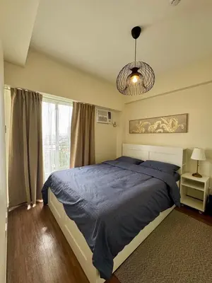 a bedroom with a large bed and a window at Metro Zen at DMCI Satori Residence 1br in Manila