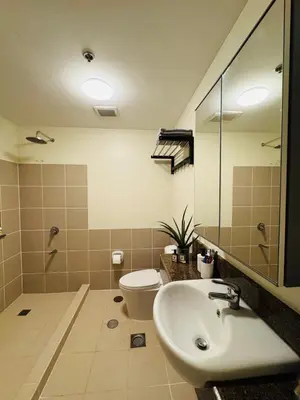 a bathroom with a sink and a toilet and a mirror at Metro Zen at DMCI Satori Residence 1br in Manila