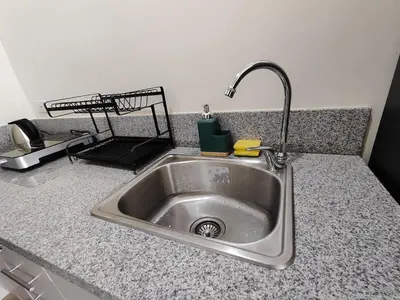 a kitchen sink with a faucet on a counter at Sweet, Simple and Stylish Studio in Silang