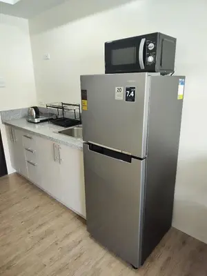 a microwave on top of a refrigerator in a kitchen at Sweet, Simple and Stylish Studio in Silang