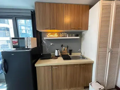 a small kitchen with a sink and a refrigerator at Stylish unit in Ortigas near podium & holiday inn in Manila