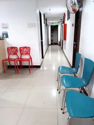 a corridor of a hospital with red and blue chairs at Harrison Suites in Manila