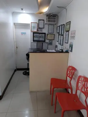 a waiting room with a counter and red chairs at Harrison Suites in Manila