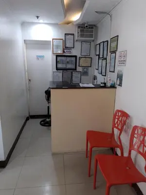 a waiting room with a counter and red chairs at Harrison Suites in Manila