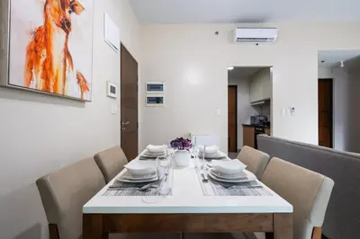 a dining room with a white table and chairs at One Uptown Residence BGC 2BR Cor unit with balcony ,washer in Manila