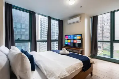a bedroom with a bed and a flat screen tv at One Uptown Residence BGC 2BR Cor unit with balcony ,washer in Manila