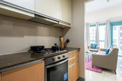 a kitchen with a stove and a counter top at One Uptown Residence BGC 2BR Cor unit with balcony ,washer in Manila