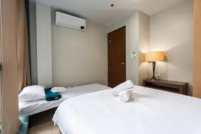 two beds in a hotel room with white sheets at One Uptown Residence BGC 2BR Cor unit with balcony ,washer in Manila