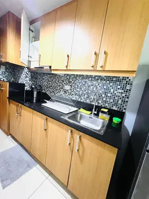 a kitchen with a sink and wooden cabinets at Sea Residence MOA Prime by Paul in Manila