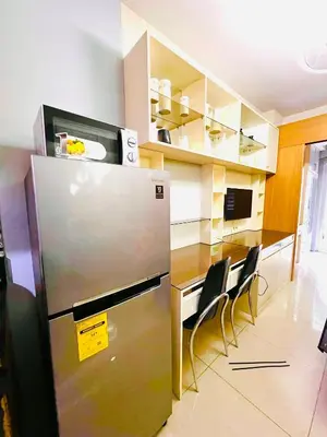 a kitchen with a refrigerator and a counter with chairs at Sea Residence MOA Prime by Paul in Manila