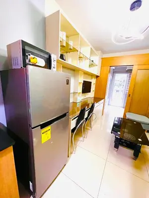 a kitchen with a refrigerator and a table and chairs at Sea Residence MOA Prime by Paul in Manila