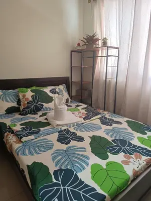 a bed with a flowered blanket with a hat on it at Shell Residences By Jhem Place in Manila