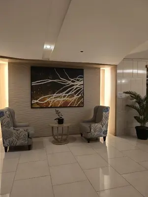 a lobby with two chairs and a table and a painting at Shell Residences By Jhem Place in Manila
