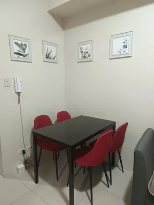 a dining room with a black table and red chairs at Shell Residences By Jhem Place in Manila