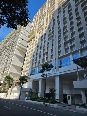 a tall building with a tree in front of it at Condo Suite 1 Bedroom McKinley West Taguig City in Manila