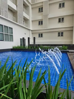 a swimming pool in front of a building with a fountain at Condo Suite 1 Bedroom McKinley West Taguig City in Manila