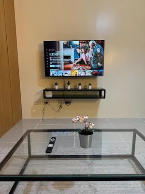 a tv sitting on a wall with a glass table at Spacious pool view at Mall of Asia 100mb Netflix in Manila
