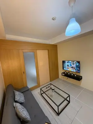 a living room with a couch and a tv at Spacious pool view at Mall of Asia 100mb Netflix in Manila