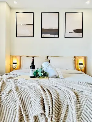 a bedroom with a white bed with three pictures on the wall at Exquisite Japandi 2 & Mediterranean Breeze at Venice w Grand Canal View! in Manila