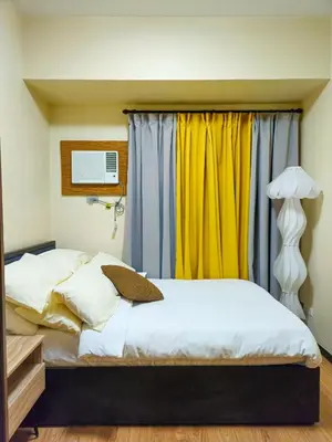 a bedroom with two beds and a yellow curtain at Galini Suites in Manila