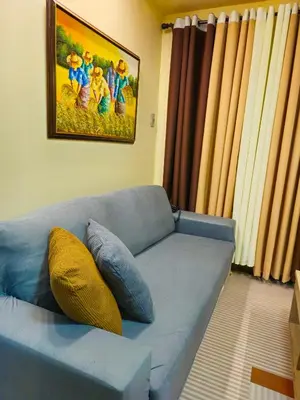 a blue couch with two pillows sitting in a living room at Galini Suites in Manila