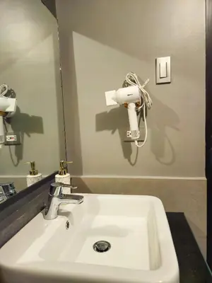 a white sink in a bathroom with a mirror at Galini Suites in Manila