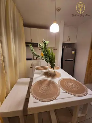 a kitchen table with two plates and a plant on it at El Nissi Staycation, THE BARIQUIT SUITE, Enchanted Kingdom in Santa Rosa