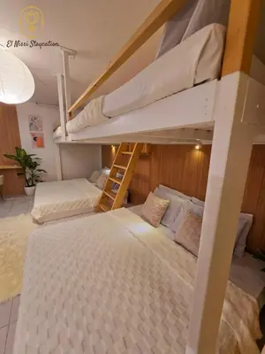 a bedroom with two bunk beds and a ladder at El Nissi Staycation, THE BARIQUIT SUITE, Enchanted Kingdom in Santa Rosa