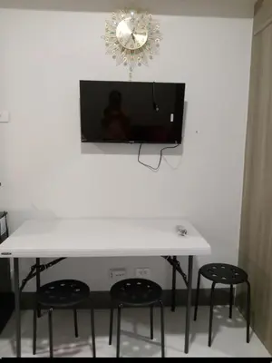 a white table with two chairs and a tv on a wall at One Bedroom Unit in Fame Residences in Manila