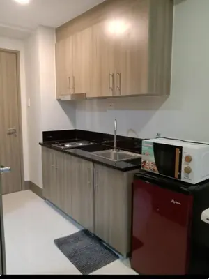 a kitchen with wooden cabinets and a sink and a microwave at One Bedroom Unit in Fame Residences in Manila