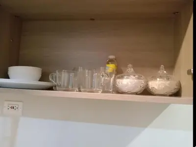 a shelf with bowls and other glass items on it at One Bedroom Unit in Fame Residences in Manila