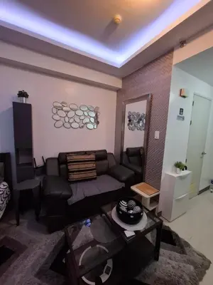a living room with a couch and a table at QUINS STAYCATION One Bedroom at SMDC South Residences in Manila