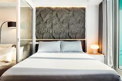 a bedroom with a large white bed and a wall at Casa Attila - Azure Urban Resort Residences in Manila