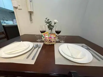 a table with two white plates and two glasses of wine at AIR Residences Makati Holiday Home in Manila