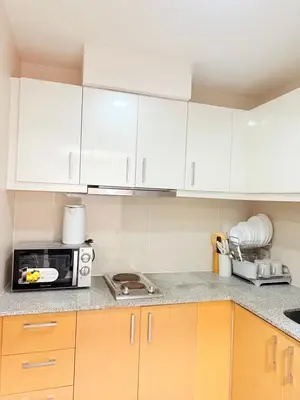 a kitchen with white cabinets and a microwave at Relaxing and Comfy in Manila
